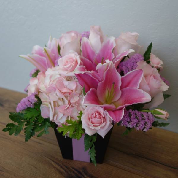 Pink lilies and roses arranged in a black box