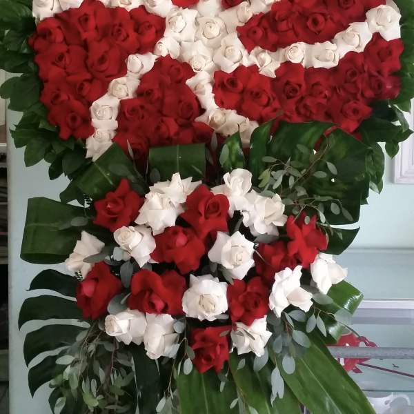 Large standing floral wreath of red and white roses with green foliage