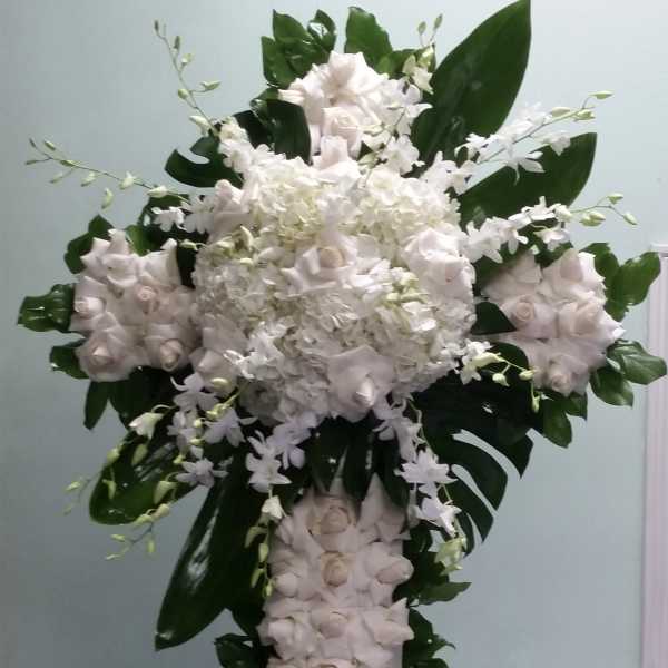 Tall white floral cross with roses and orchids