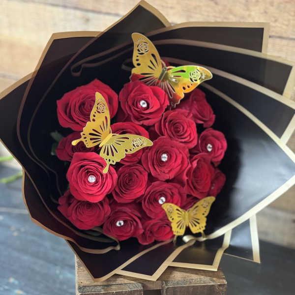 Bouquet of red roses wrapped in black paper with gold butterfly accents