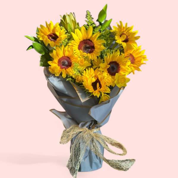 Bouquet of yellow sunflowers wrapped in gray paper with a gold ribbon