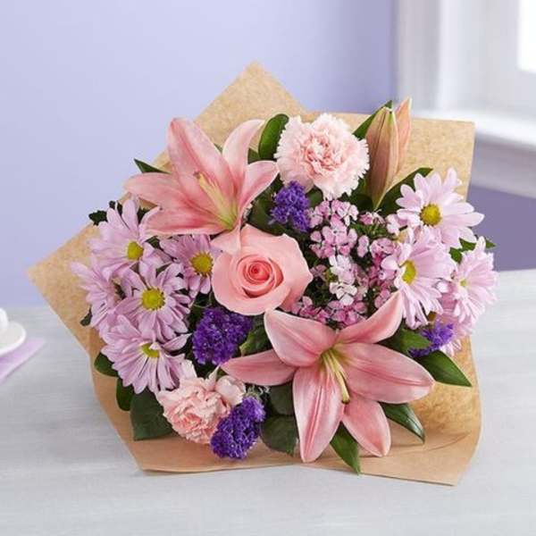Pink lilies, roses, and daisies in kraft paper wrapping