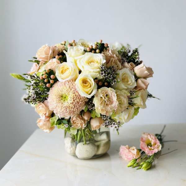 Blush and cream rose bouquet in a glass vase with small pink blooms