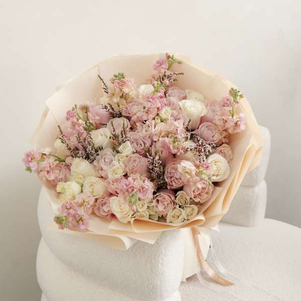 Bouquet of pink and white roses wrapped in peach paper
