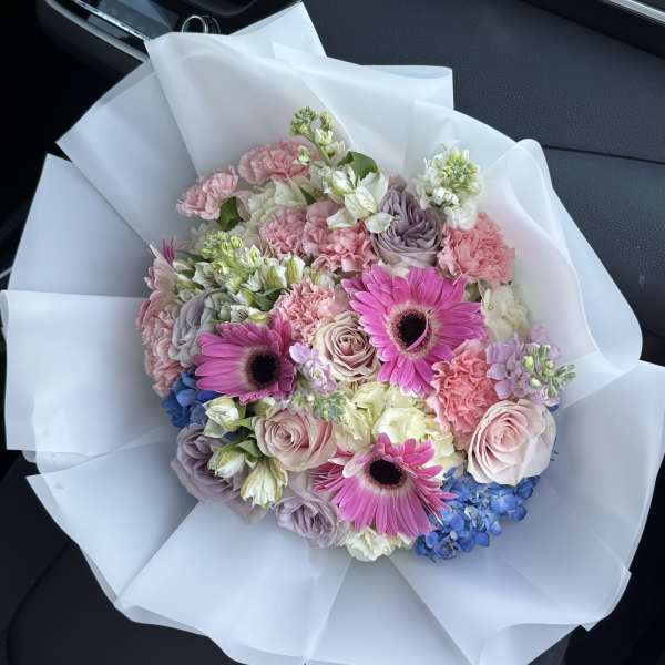 Bouquet of pink and lavender flowers wrapped in white paper