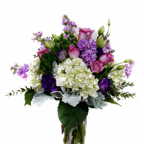 Purple and white floral arrangement in a clear glass vase