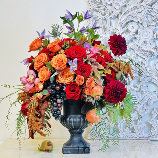 Large mixed bouquet of red, orange, and pink flowers in a black vase