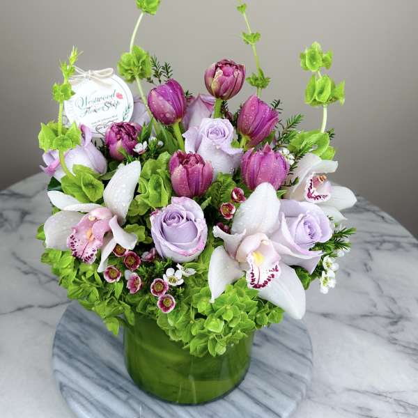 Pink and lavender flowers arranged in a green glass vase