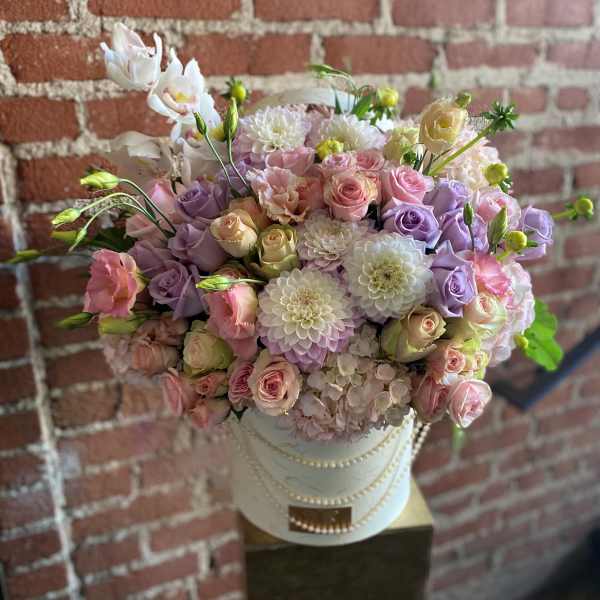 Pastel bouquet of roses, dahlias, and orchids in a white hatbox