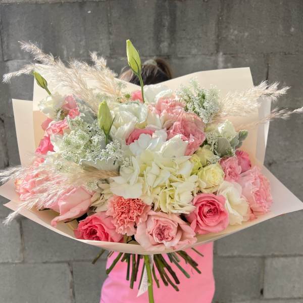 Large bouquet of pink and white flowers wrapped in pale paper