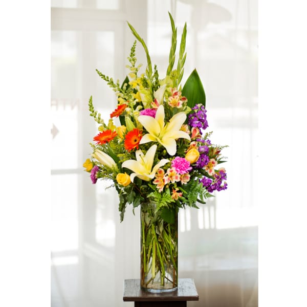 Tall mixed flower arrangement in a clear glass vase