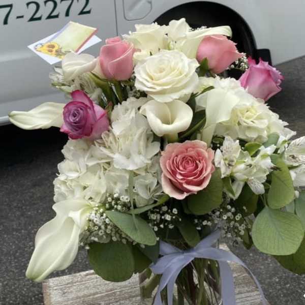 Bouquet of pink and white roses with calla lilies in a glass vase