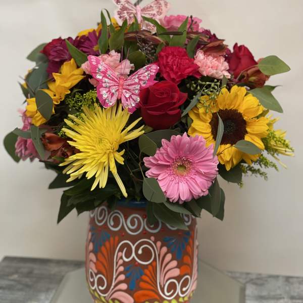 Colorful mixed bouquet in a decorated vase with butterfly picks