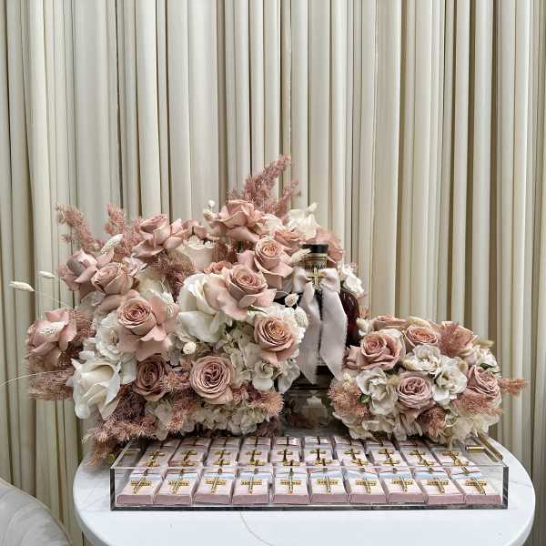 Pink and white rose arrangements with gift boxes on a table