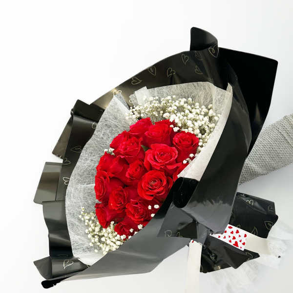 Bouquet of red roses with white baby's breath in black wrapping