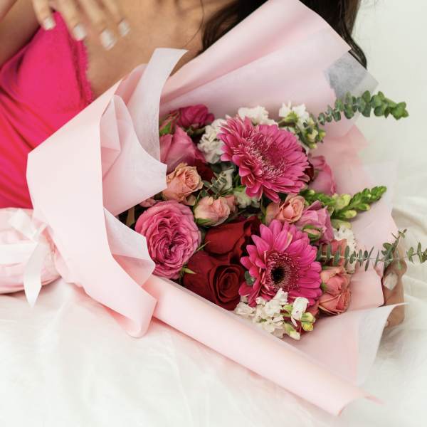 Pink bouquet with roses and gerbera daisies wrapped in pale pink paper