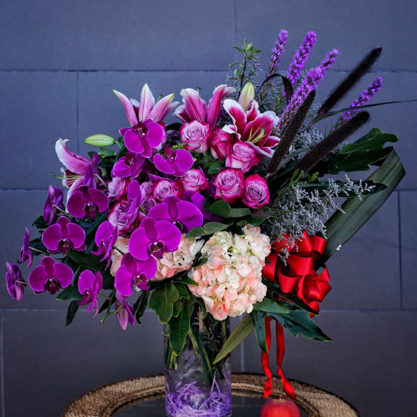 Bouquet of pink lilies, roses, orchids, and hydrangea in a glass vase
