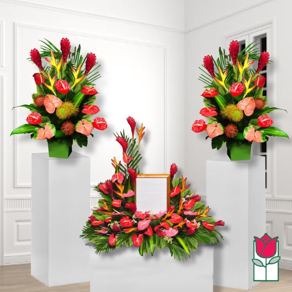 Tropical floral funeral display with red and pink blooms on pedestals