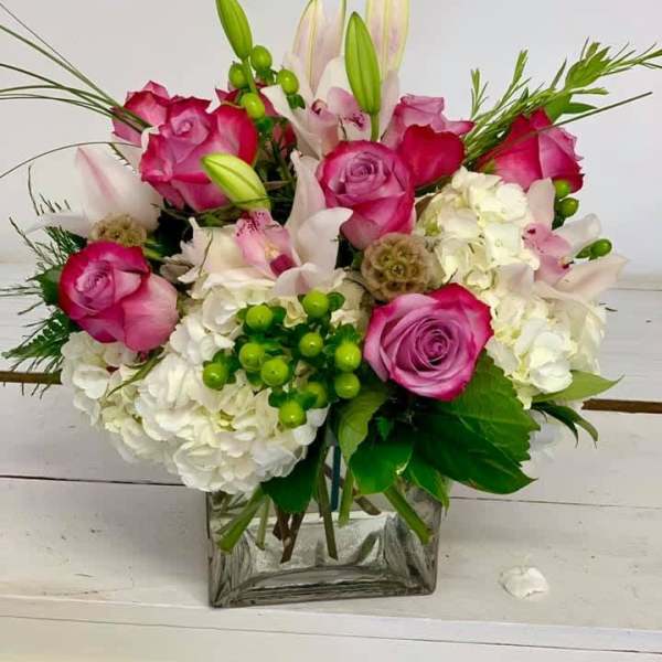 Pink roses and white lilies in a square glass vase