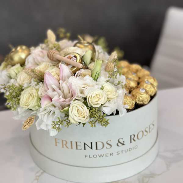 Round box of white and blush roses with gold chocolates on top