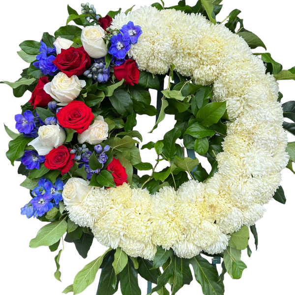 Heart-shaped floral wreath with white chrysanthemums, red and white roses, and blue flowers