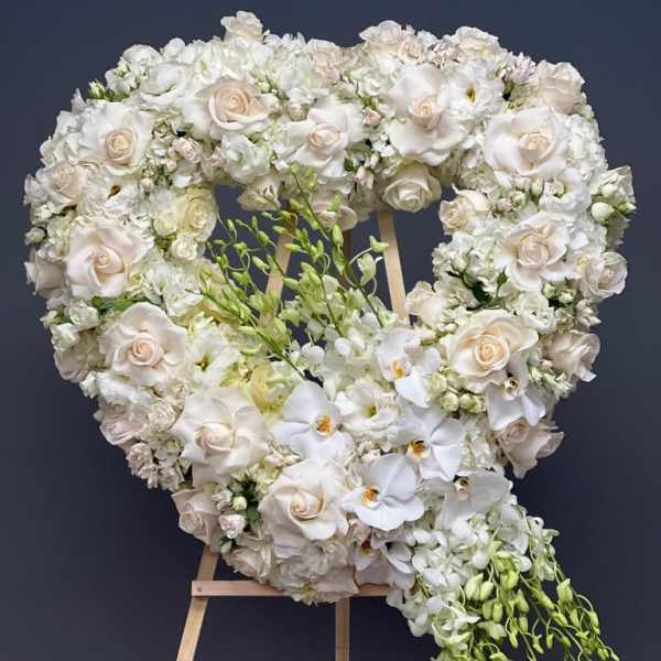 Heart-shaped white floral wreath on a wooden easel