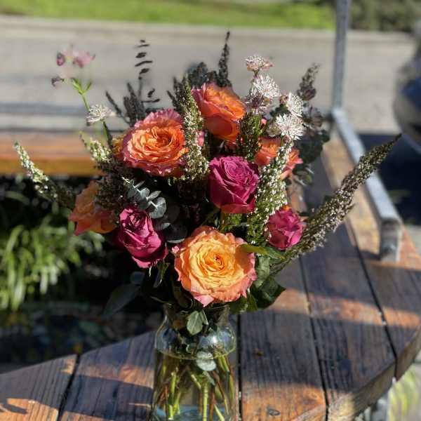 Bouquet of orange and pink roses in a glass vase