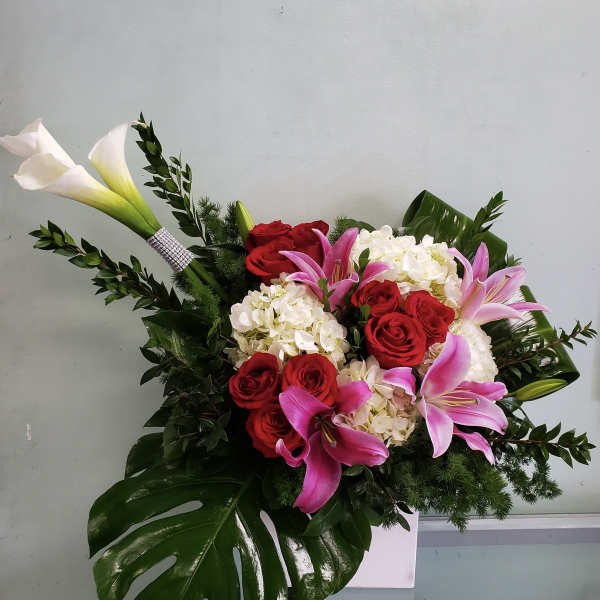 Bouquet of red roses, pink lilies, and white calla lilies in a white vase