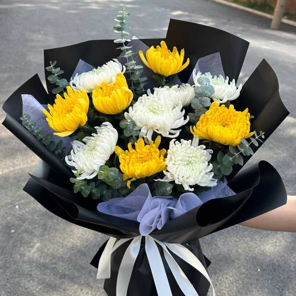 Bouquet of yellow and white chrysanthemums wrapped in black paper