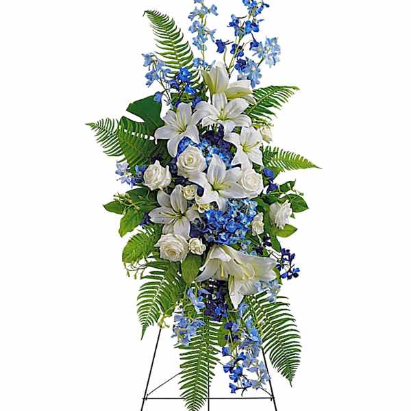 Tall standing floral spray with white lilies, white roses, and blue flowers