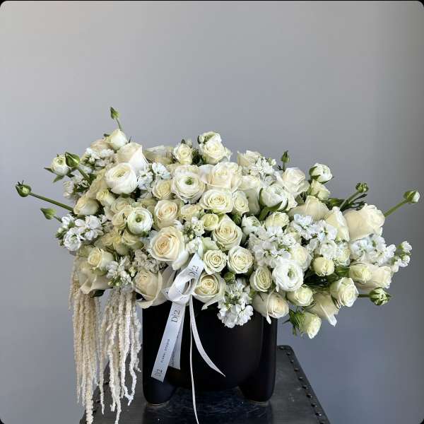 Cream rose bouquet in a black container with white ribbon