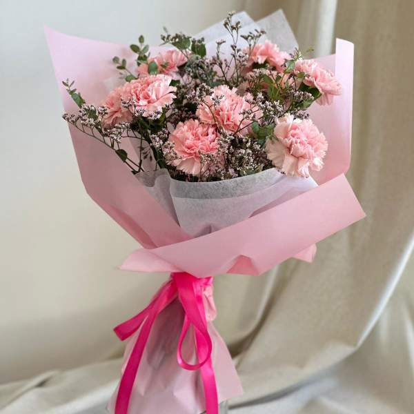 Pink carnation bouquet wrapped in pastel paper with a ribbon