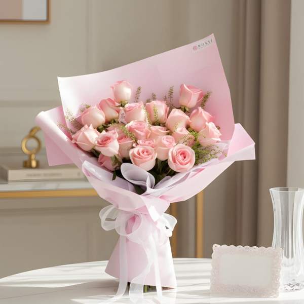 Bouquet of pale pink roses wrapped in pink paper with a white ribbon