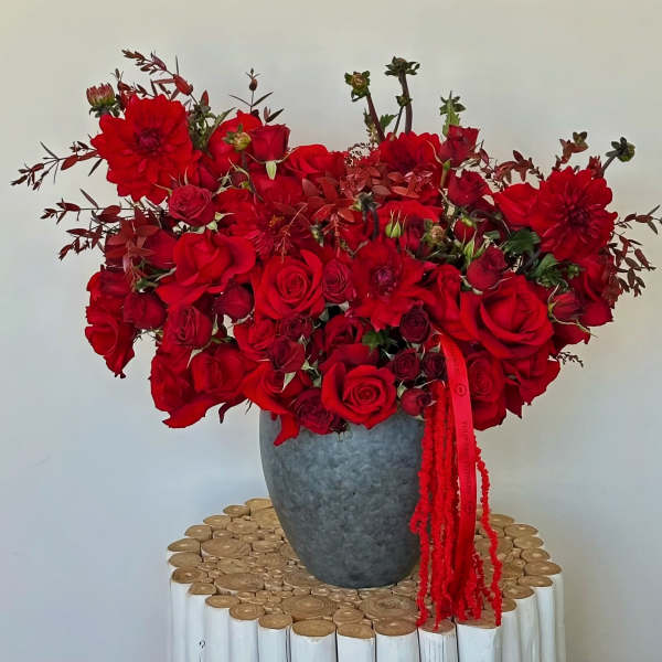 Red rose and dahlia arrangement in a gray vase