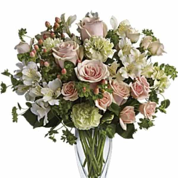 Pink roses and white flowers arranged in a clear glass vase