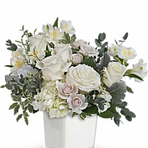 White roses and lilies in a clear square vase