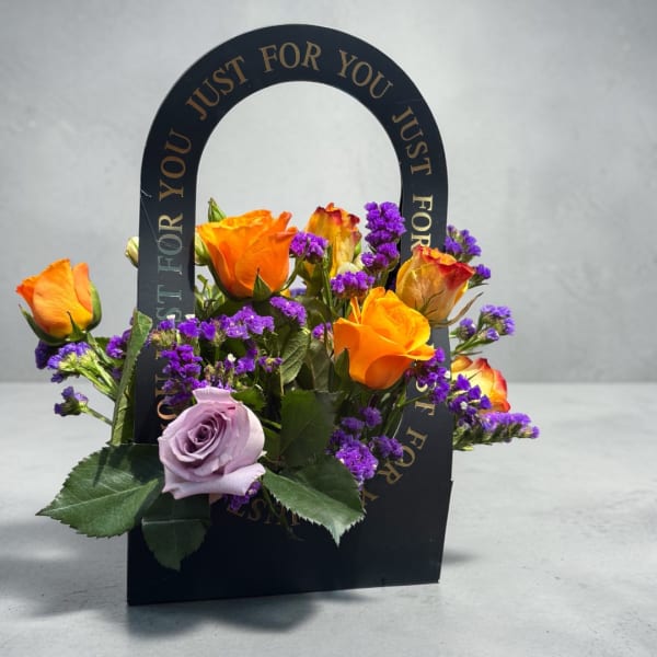 Orange and lavender roses arranged in a black handled box