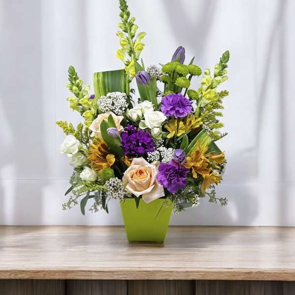 Mixed bouquet in a lime green vase with purple, white, and yellow flowers