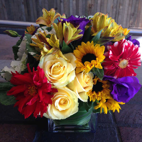 Mixed bouquet of roses, daisies, and alstroemeria in a glass vase