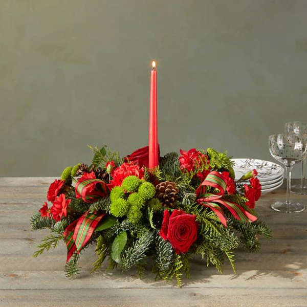 Holiday centerpiece with red roses and a lit red taper candle
