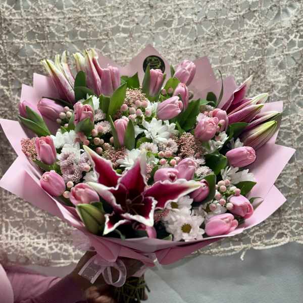 Pink tulip bouquet with white daisies and a dark lily in pink wrap