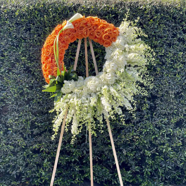 Orange and white floral wreath on a wooden easel