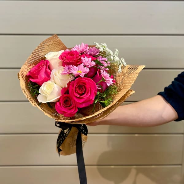 Handheld bouquet of pink and white roses with small pink daisies
