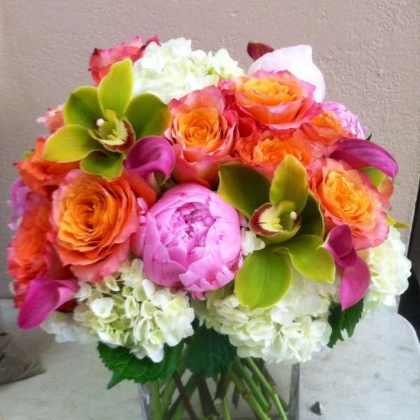 Bouquet of orange and pink roses with white hydrangeas in a glass vase