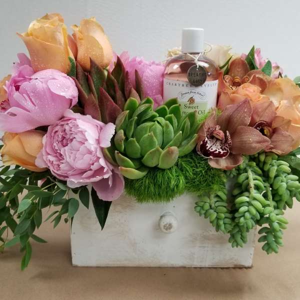 Flower arrangement in a white drawer box with a bottle of sweet almond oil