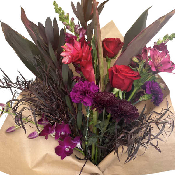 Bouquet of red roses, purple orchids, and dark foliage wrapped in kraft paper