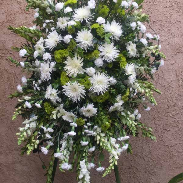 Large white and green funeral spray on a stand