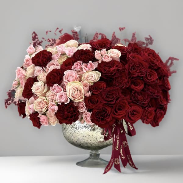 Large arrangement of red and blush roses in a silver pedestal vase