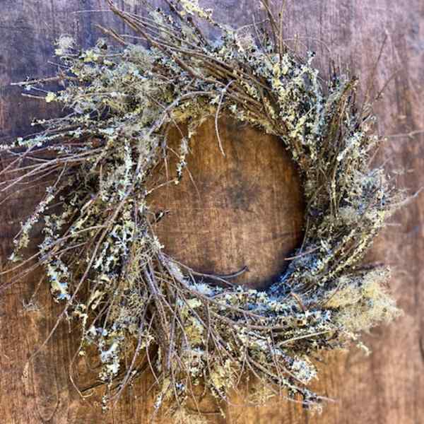 Rustic twig wreath with pale lichen on a wooden background
