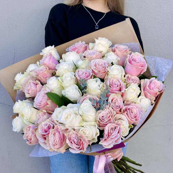 Large hand-tied bouquet of pink and white roses wrapped in kraft paper and ribbon.
